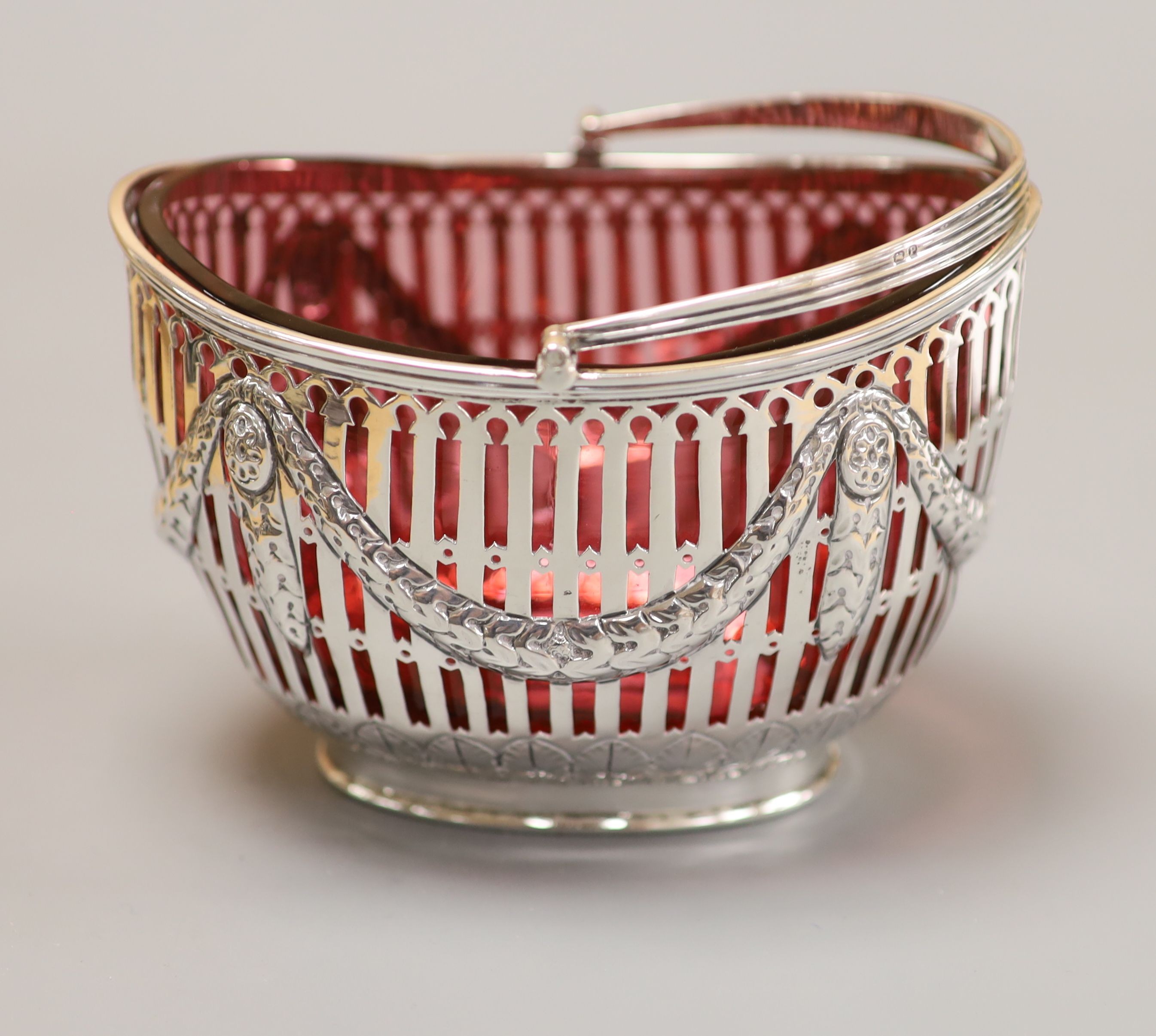A late Victorian pierced silver oval sugar basket, with cranberry glass liner, Nathan & Hayes, Chester, 1898, height 83mm, 150 grams.